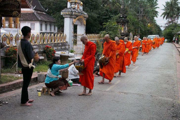 Monks walk early in the morning to receive alms of food and money in Luang Prabang, Laos