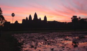 The stone temples of Angkor Wat are silhouetted by the rising sun.