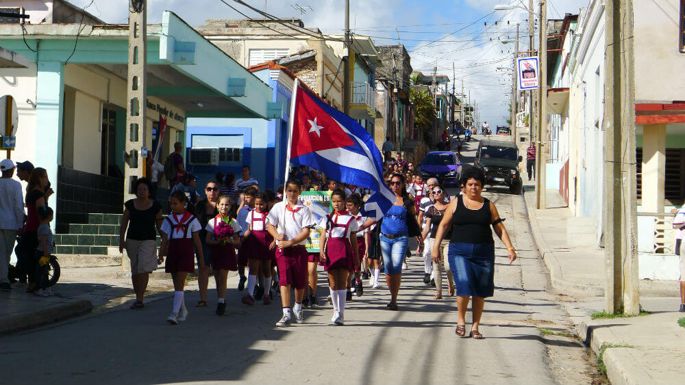 Children march with a Cuban flag to respect the fallen leader, Fidel Castro.